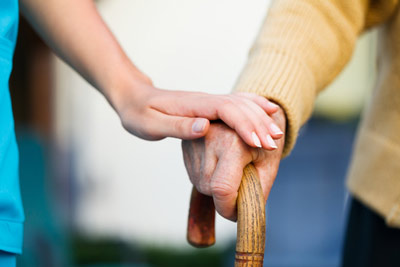 Compassionate caregiver holding hands with senior