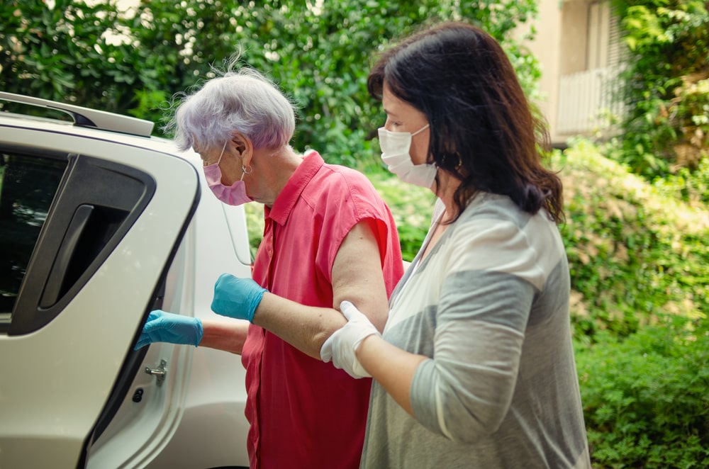 caregiver walking old person to car